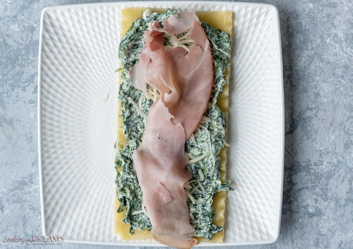 lasagna sheet covered with spinach, cheese and a slice of ham