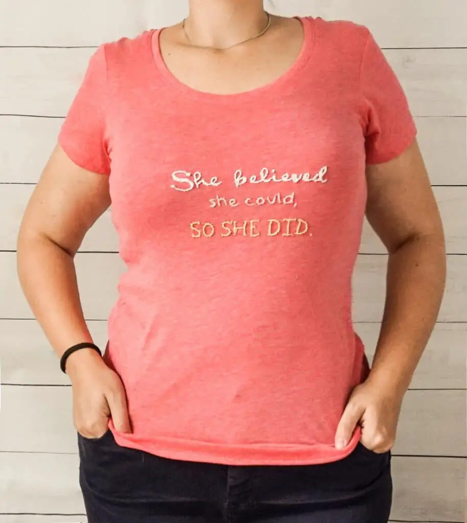 woman wearing a pink t-shirt embroidered with white and yellow text