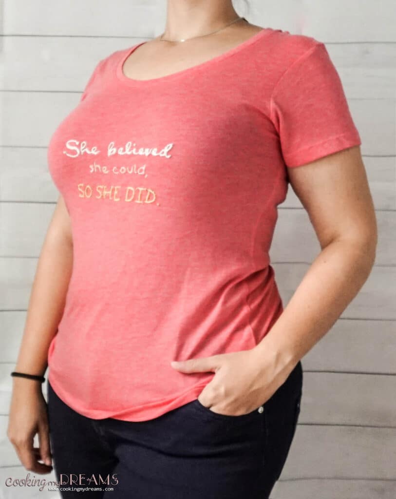 woman wearing a pink t-shirt embroidered with white and yellow text