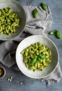 two bowls filled with creamy pesto gnocchi on a grey towel