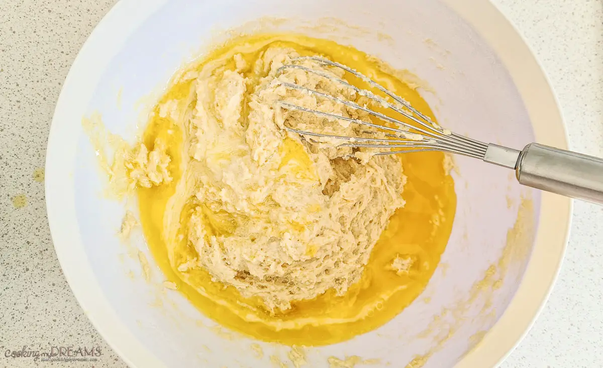 bowl of cake dough with melted butter and a whisk