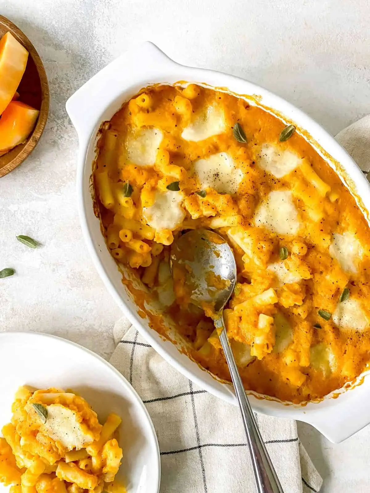 butternut squash pasta bake in a white dish with a spoon it.