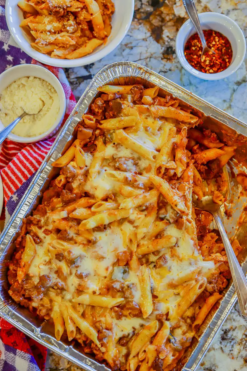 baked penne pasta with cheese, crushed pepper and other fixings on the side