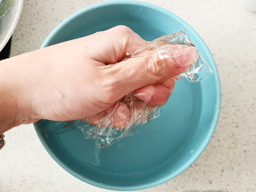 hand squeezing the gelatin out of water