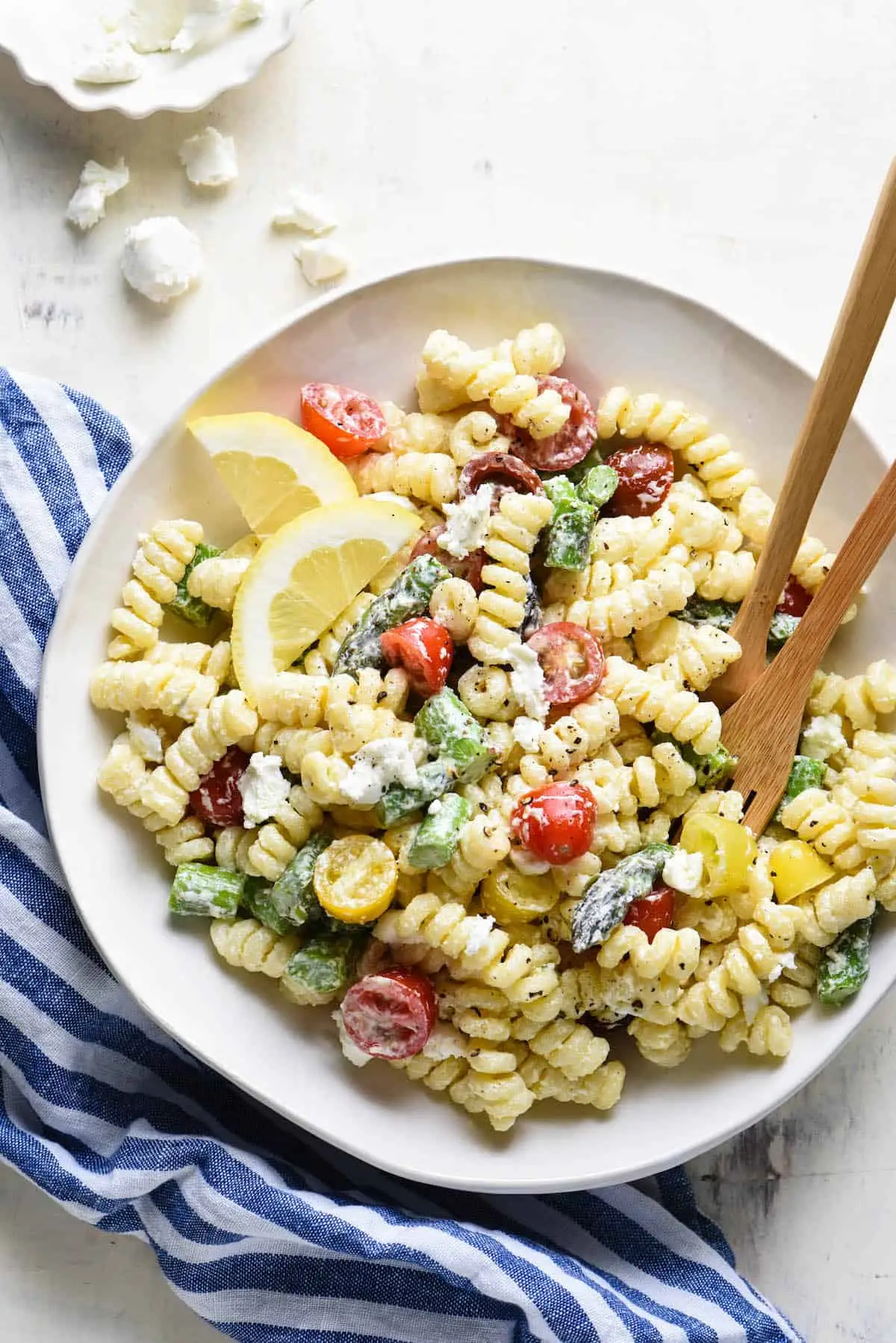 plate with pasta salad and wooden utensils sitting on a towel