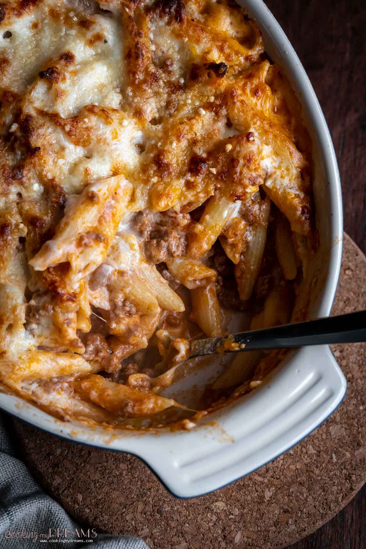 spoon taking out a portion of baked pasta from a casserole