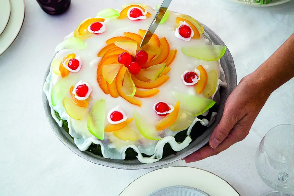 hand holding a cassata cake while knife is about to cut a slice