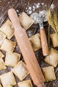 handmade ravioli on a table with a rolling pin and a cutter
