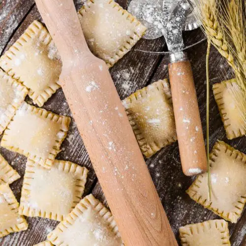 handmade ravioli on a table with a rolling pin and a cutter