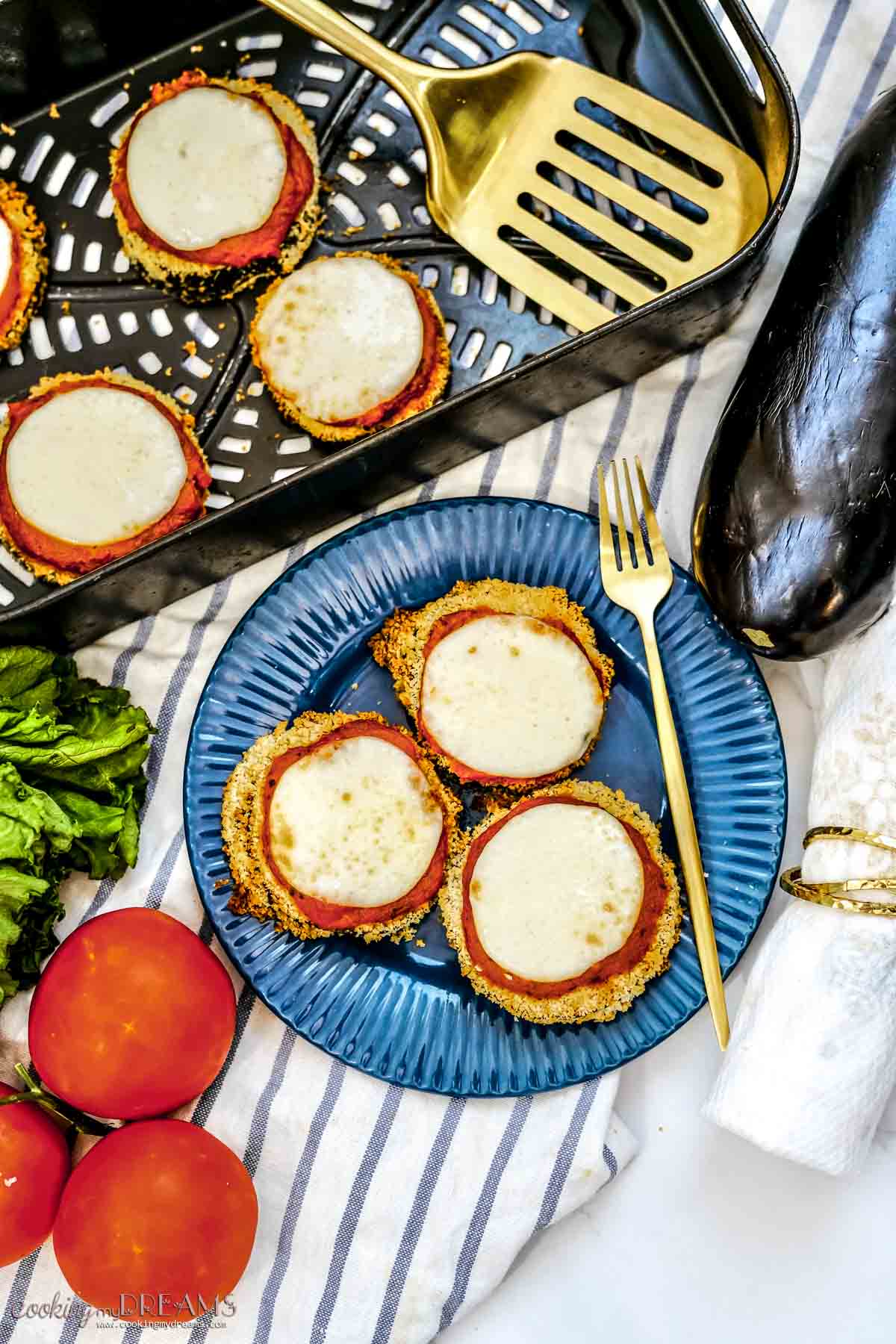 eggplant parmesan slices on a blue plate with a fork and in a air fryer basket