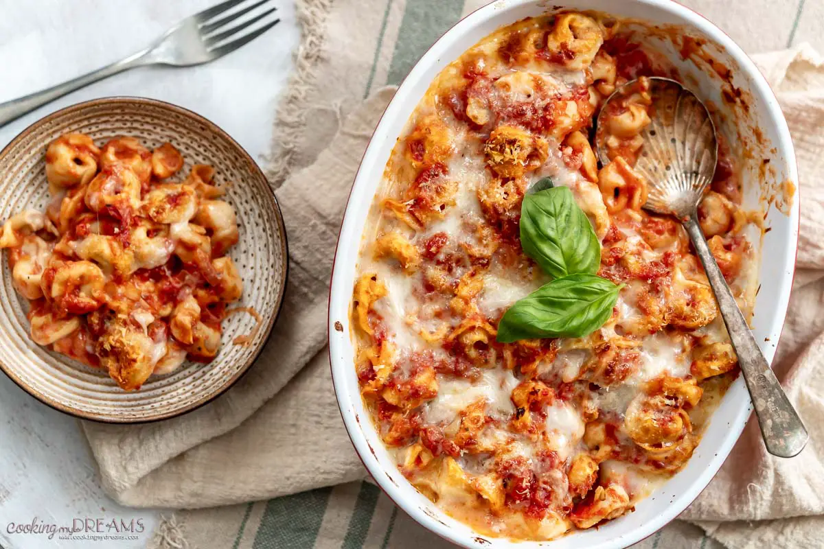 baking dish with baked tortellini next to a plate with a portion