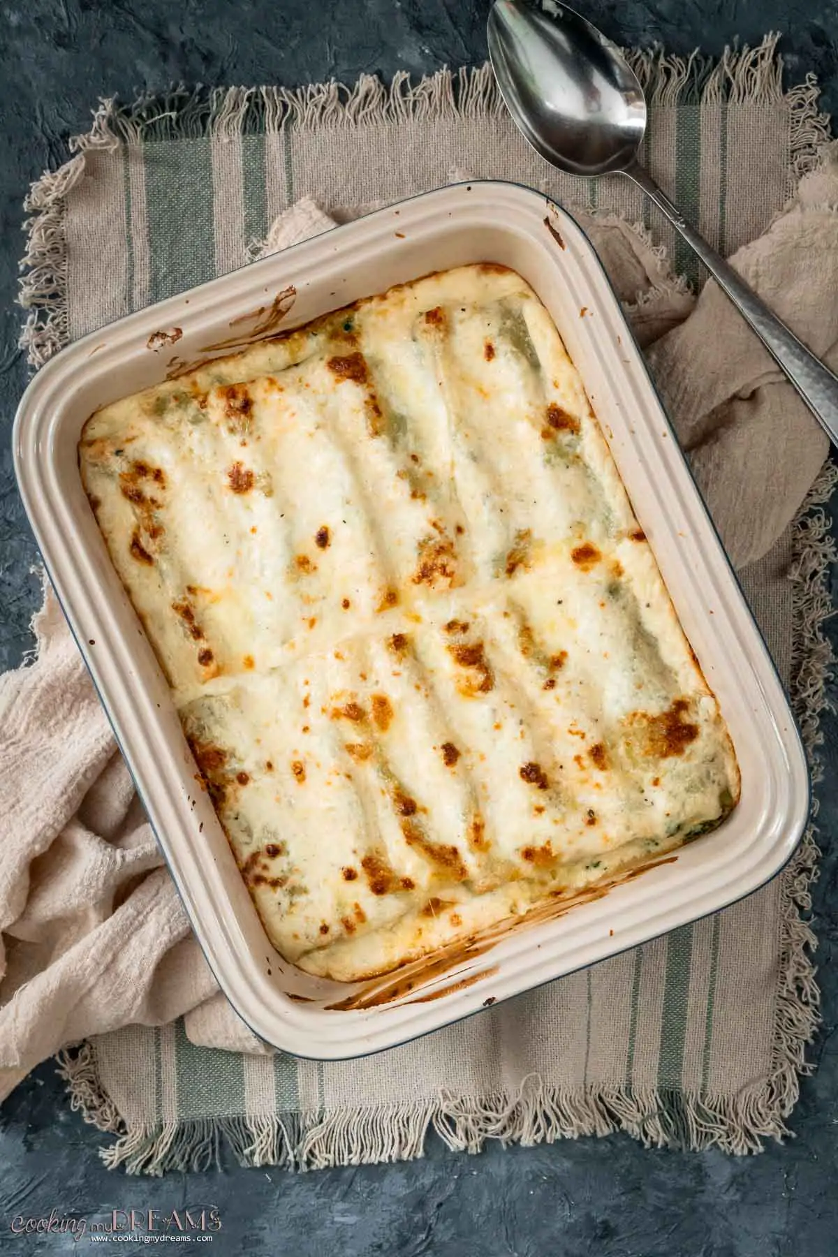 baked spinach ricotta cannelloni in a cheesy white sauce.