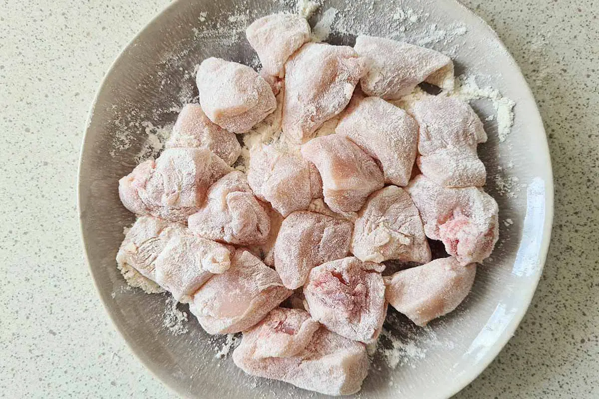 chicken breast chunks coated in flour on a plate.