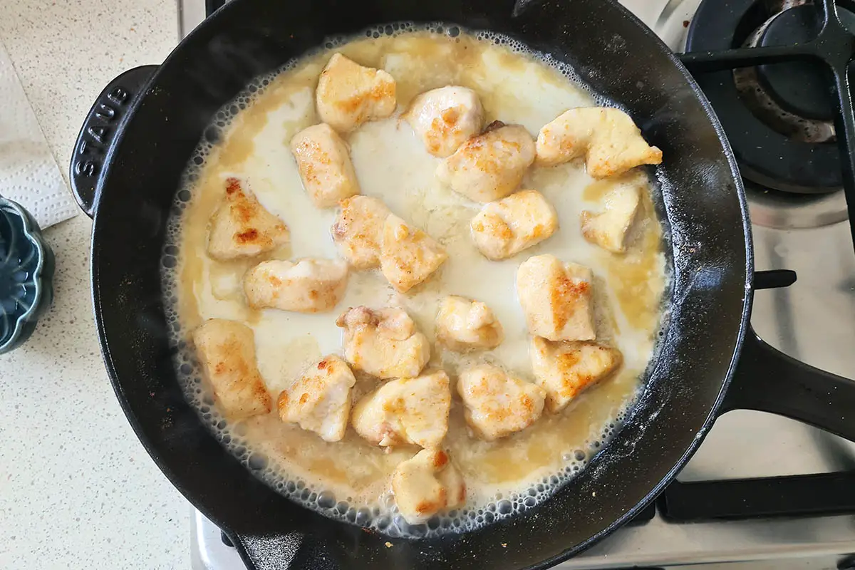 milk and lemon juice is poured in the skillet with the chicken.