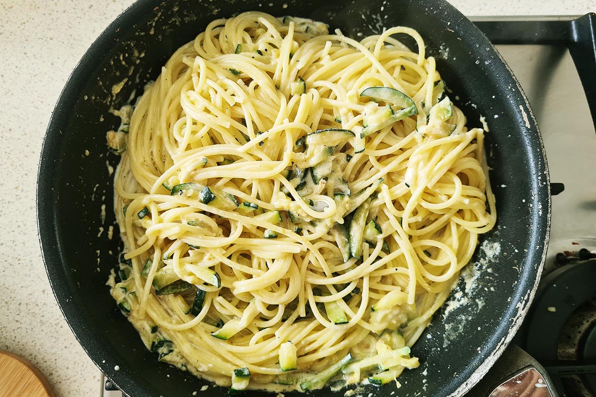 pasta is added to the pan with the creamy zucchini.