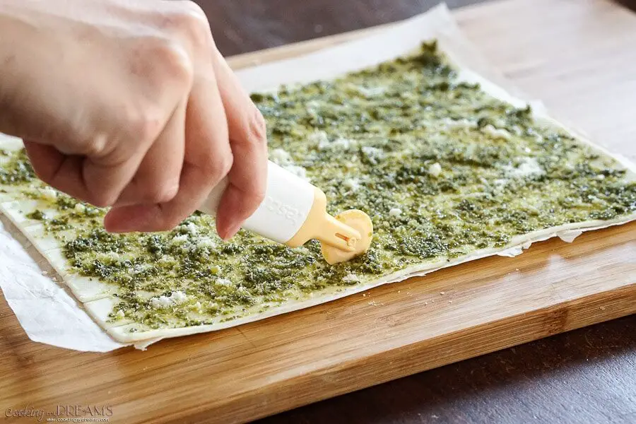 hand cutting the puff pastry in strips with a wheel cutter