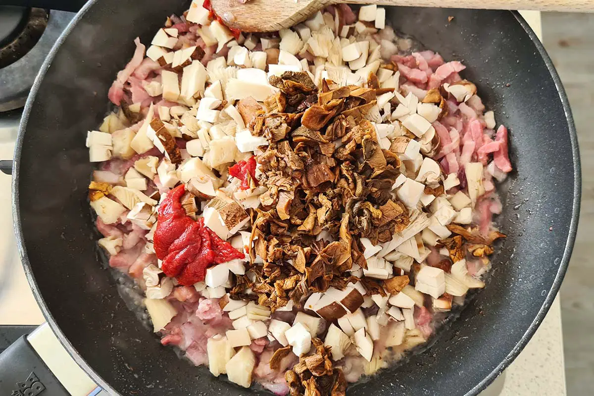 mushrooms and tomato paste are added to the pan.