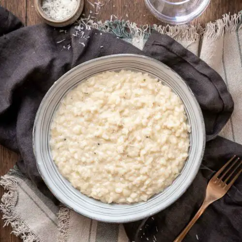 creamy garlic parmesan risotto on a plate next to a fork.