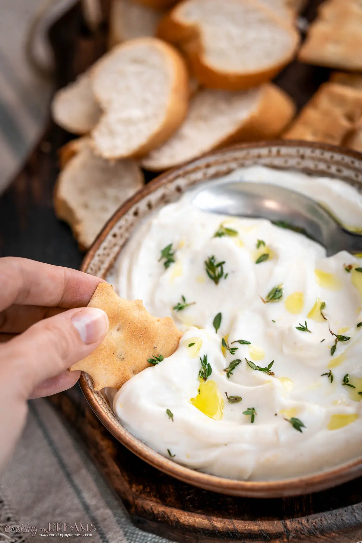 hand dipping a cracker in a bowl with whipped ricotta dip