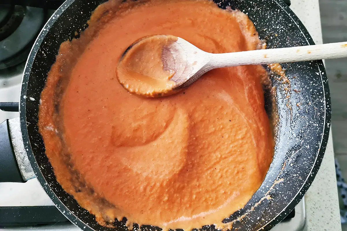 pink pasta sauce in the pan with a spoon.