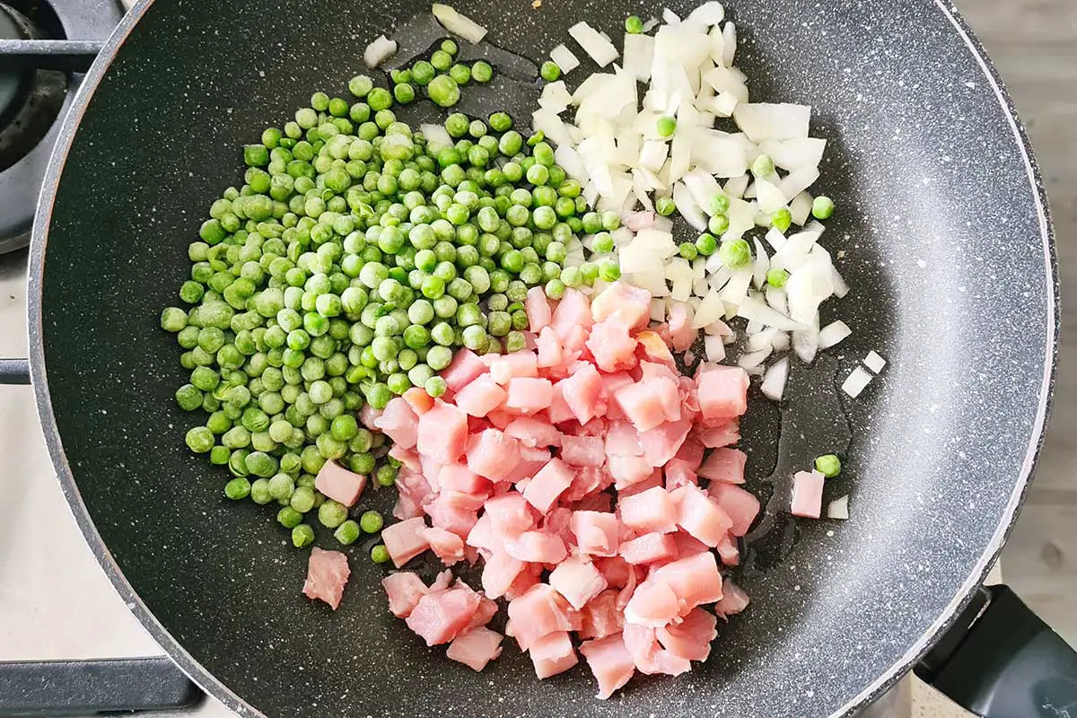 peas, onion, and ham are added into a pan.