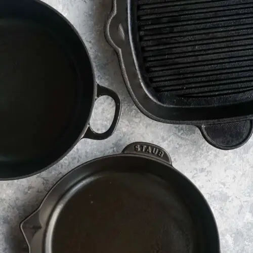 a cast iron skillet next to a cast iron dutch oven and cast iron grill pan.