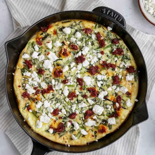 broccolini frittata in a skillet topped with feta and nduja.