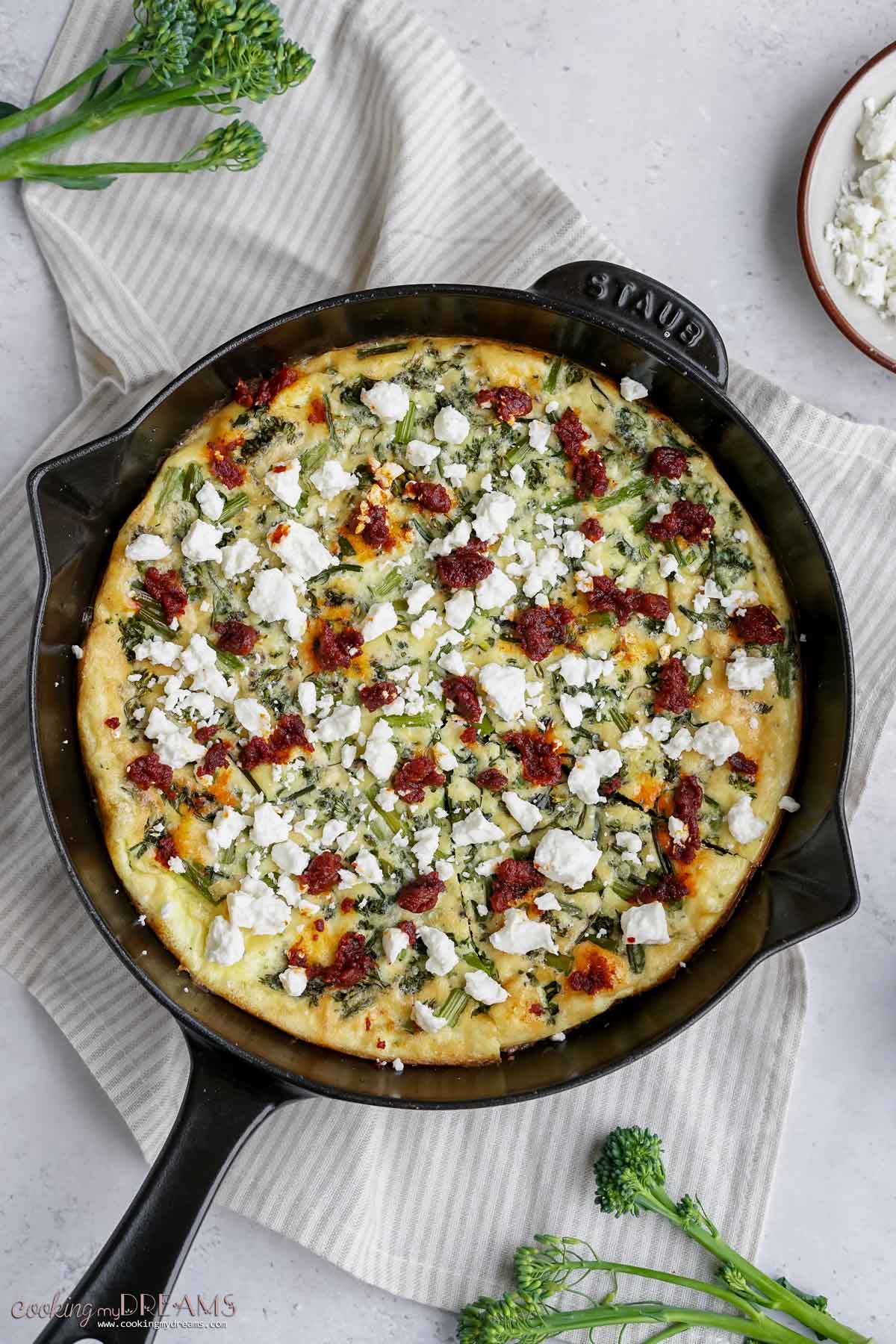 broccolini frittata in a skillet topped with feta and nduja.