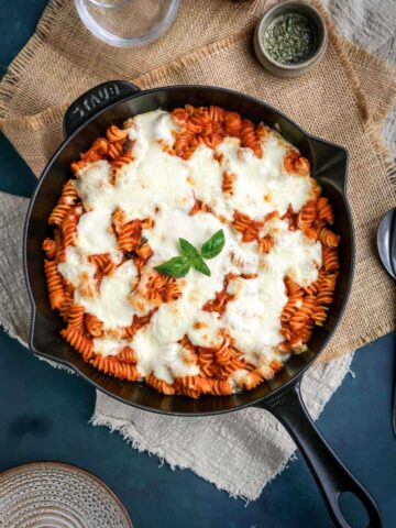 pizzaiolo pasta in a skillet topped with basil leaves.