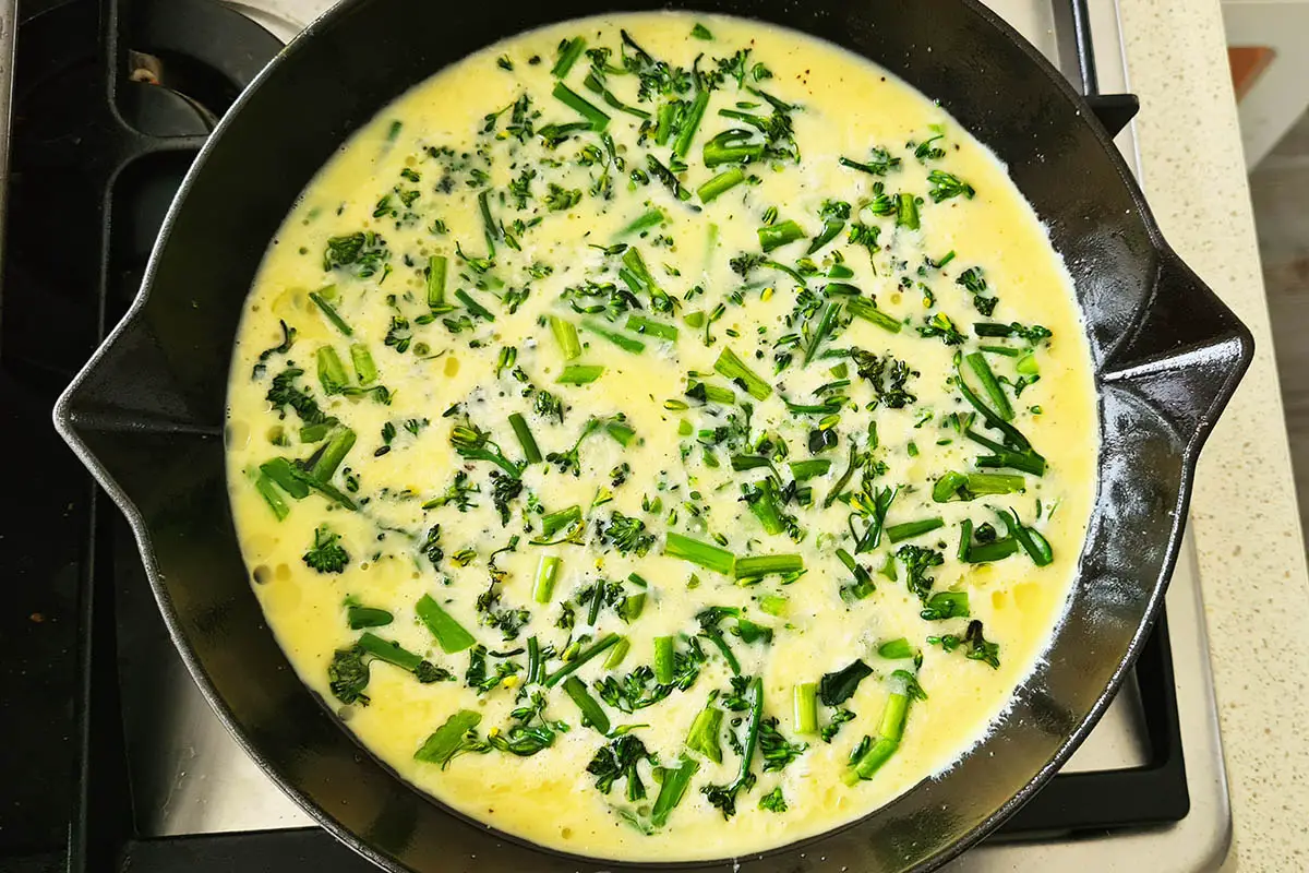 raw broccolini frittata in a skillet before baking.