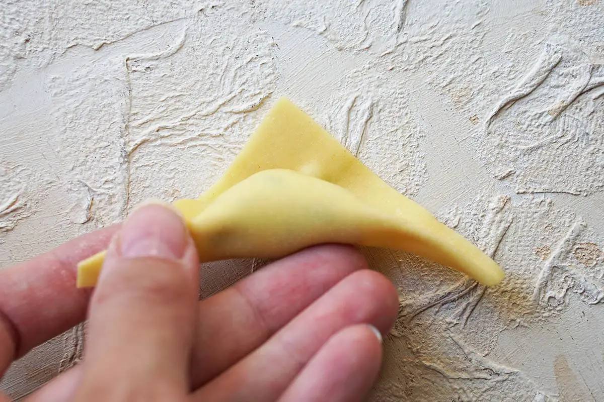 the pasta edges are pressed to fold the tortelloni.