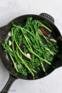 stir fried broccolini in a skillet.