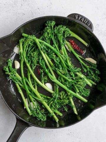 stir fried broccolini in a skillet.