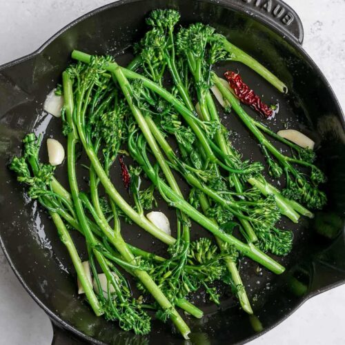 stir fried broccolini in a skillet.