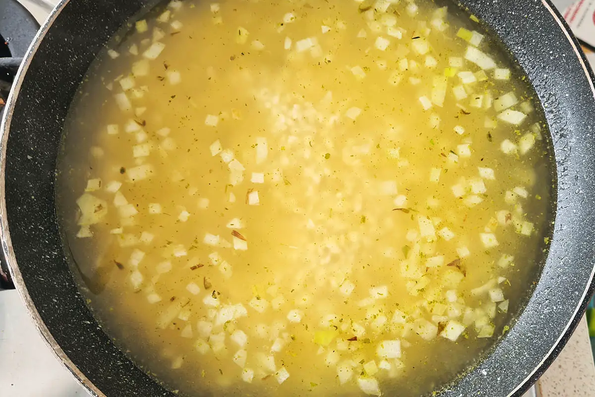 vegetable stock is added to the pan with rice.