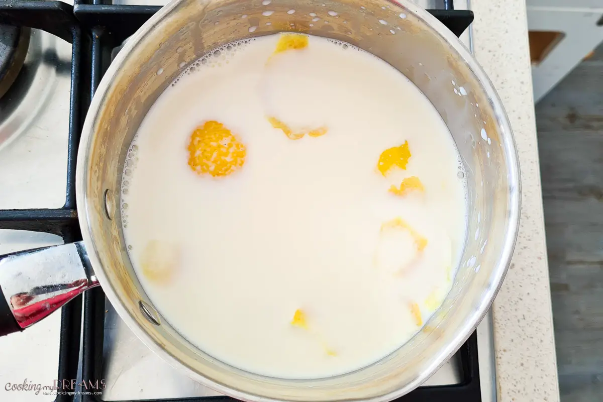 milk heating in a saucepan with lemon peel and vanilla.