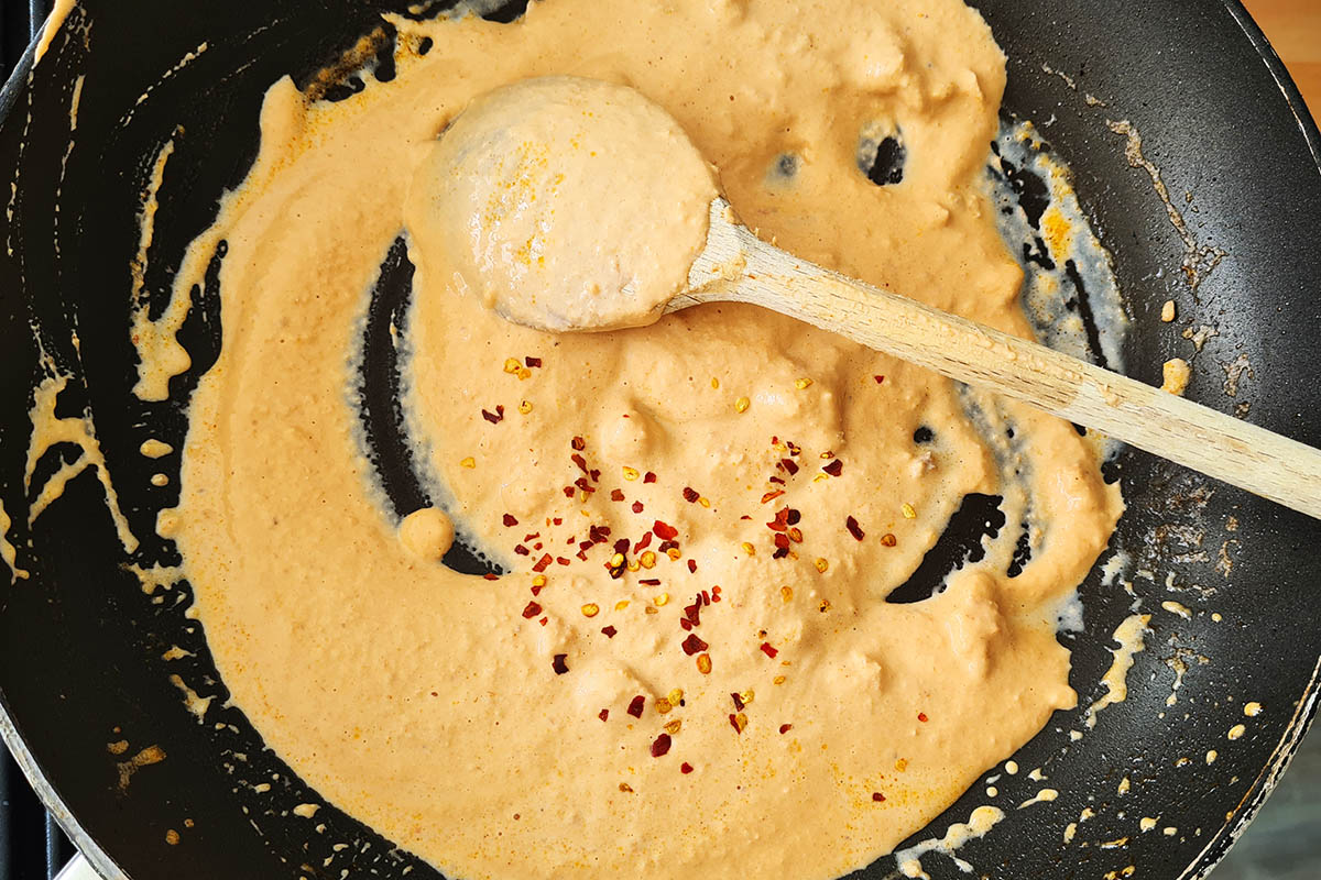 creamy salmon pasta sauce cooking with chili pepper flakes.