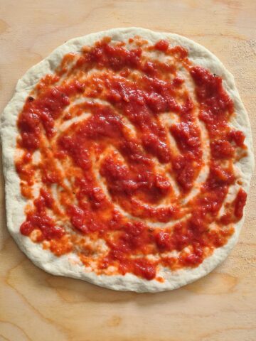 tomato sauce spreaded on raw pizza.