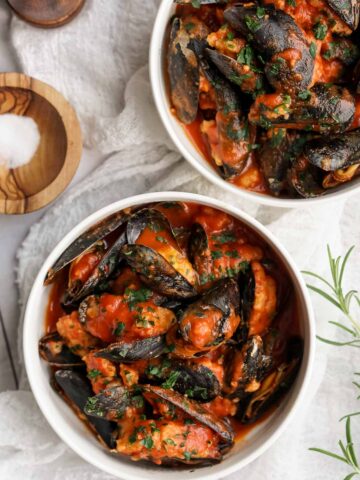 stuffed mussels in tomato sauce in two bowl.