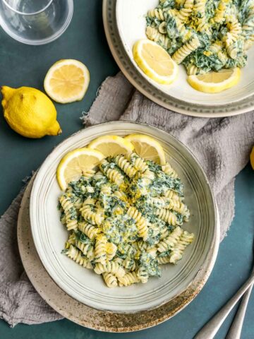 lemon ricotta pasta with spinach in two bowls with lemon slices.