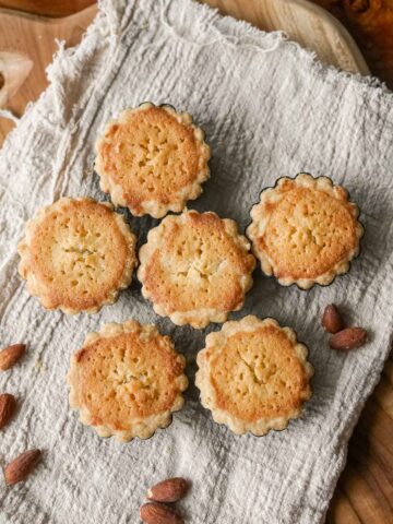 frangipane tartlets on a towel on a table.