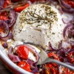 spooning taking a bite of baked ricotta with onions and tomatoes.