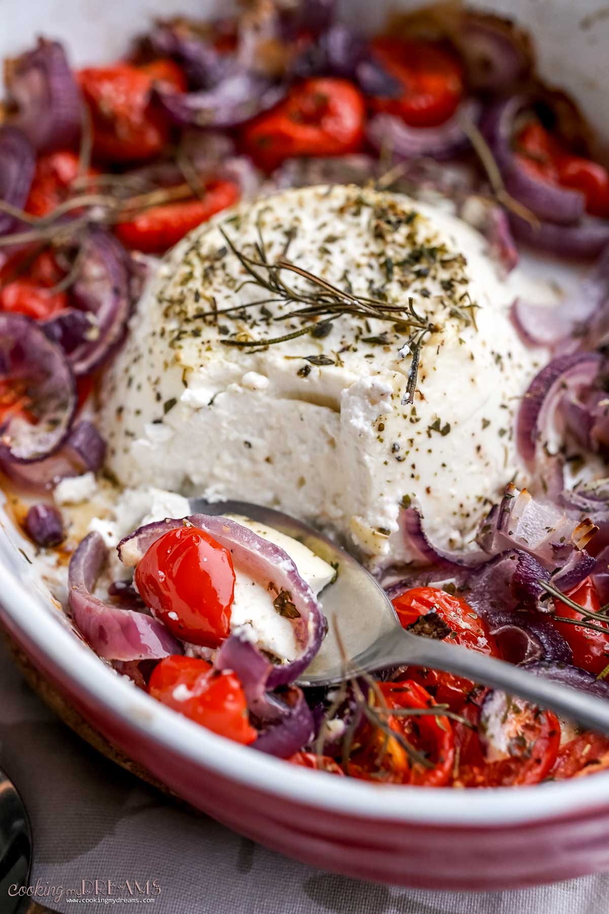 spooning taking a bite of baked ricotta with onions and tomatoes.