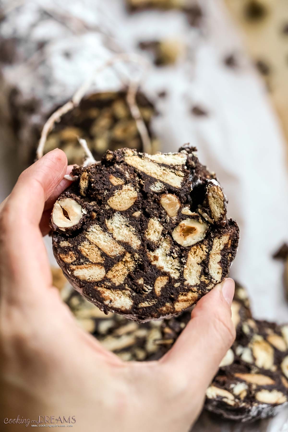 hand holding a slice of italian chocolate salami.