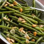 simple green beans in a serving dish with almonds and garlic.