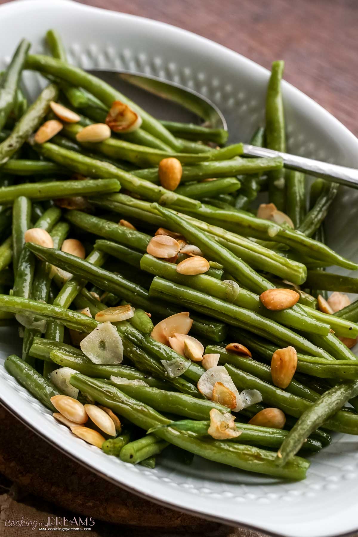 simple green beans in a serving dish with almonds and garlic.