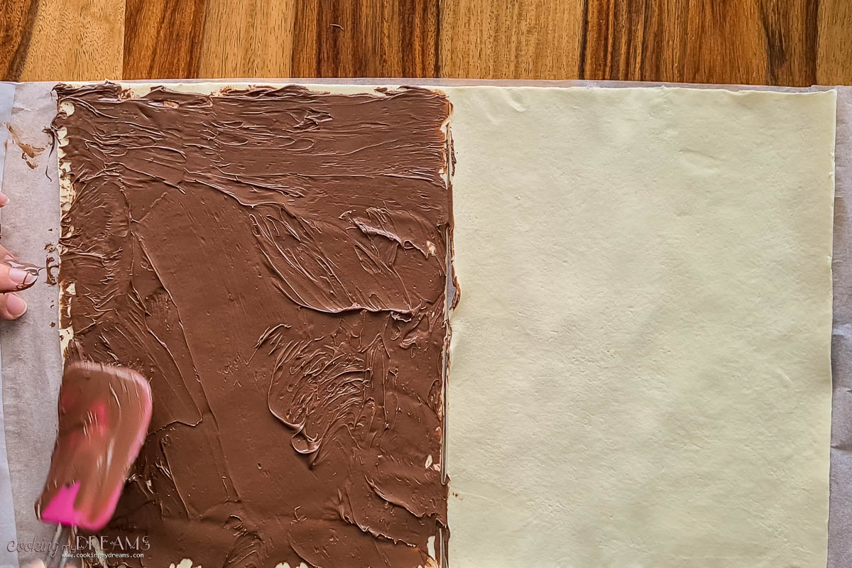 spreading nutella over half puff pastry sheet.
