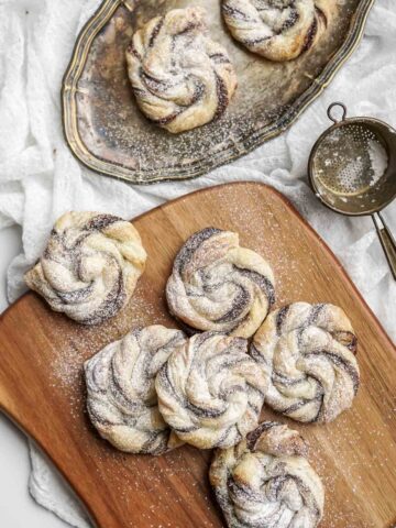 nutella puff pastries dusted with powder sugar on a wooden board.