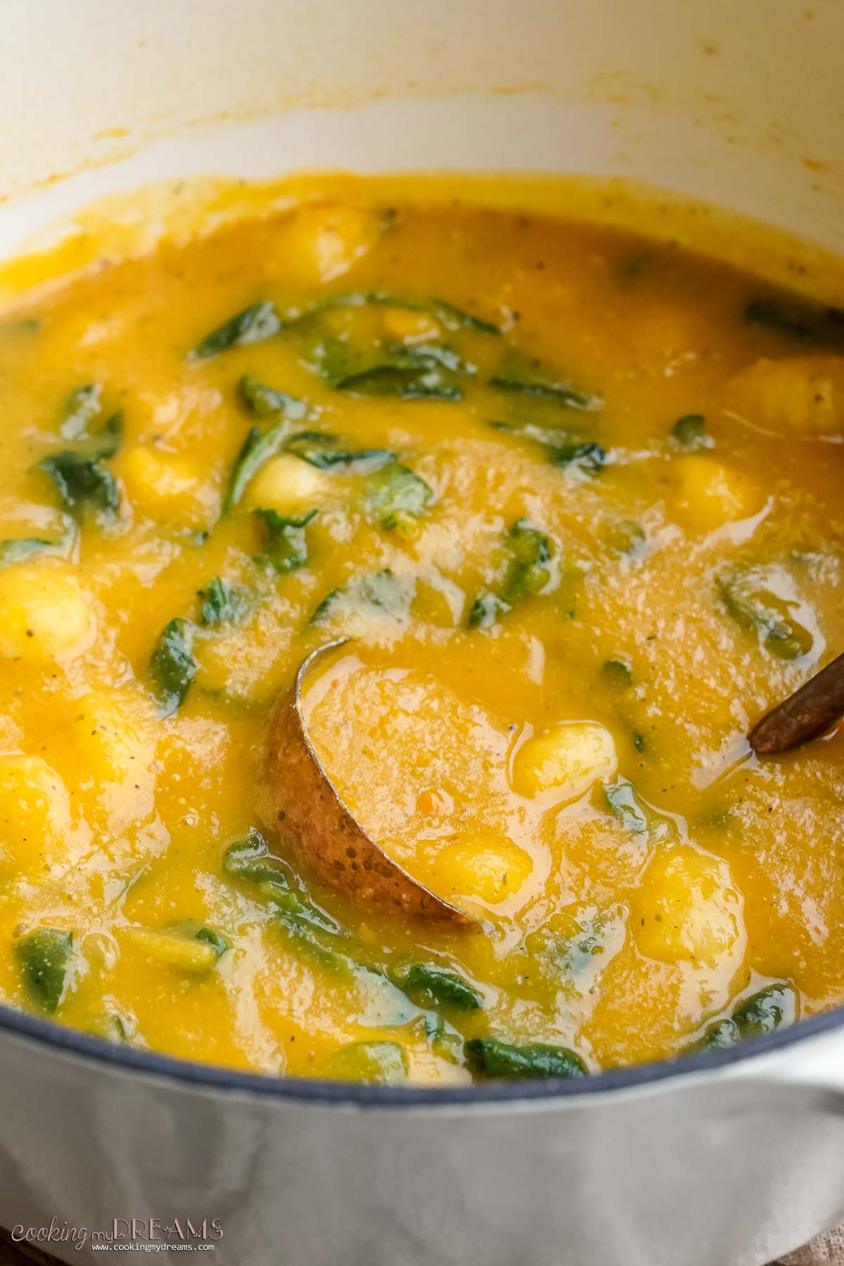 ladle inside a dutch oven with pumpkin gnocchi soup