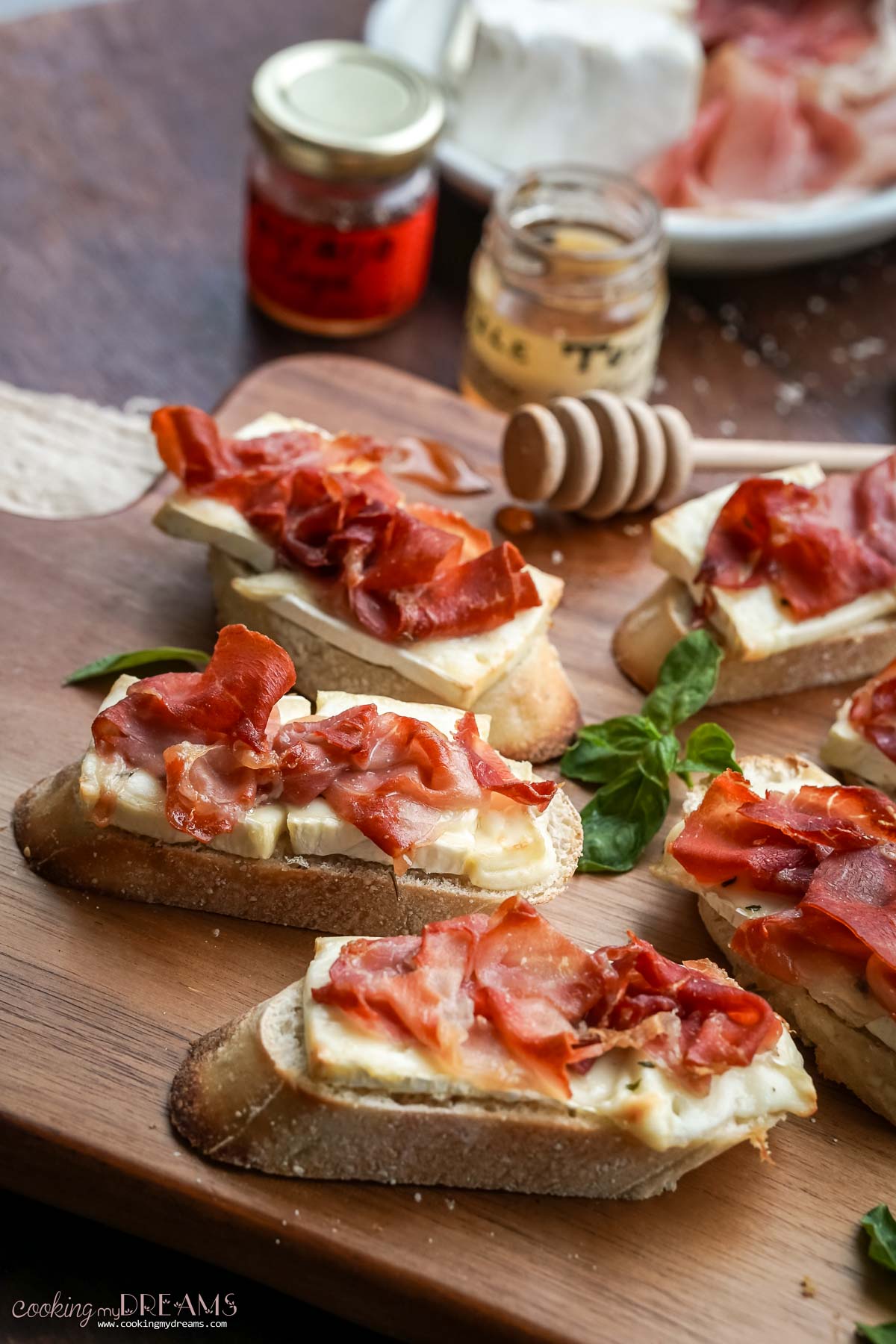 baked brie and prosciutto crostini on a wooden board.